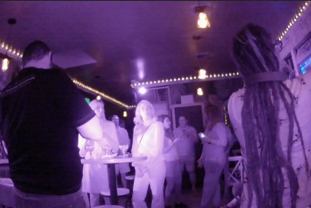 The image captures a group of people in an indoor setting possibly at a social gathering or event taken in low-light conditions using what appears to be an infrared or night-vision camera