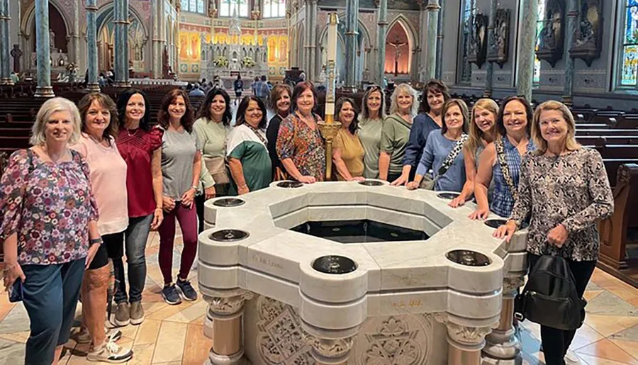 A group of women are posing for a photo around a baptismal font inside a beautifully decorated church.