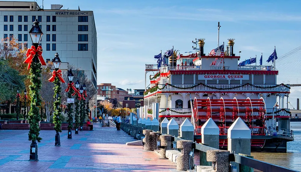 The image shows a festive riverwalk with Christmas decorations and a moored paddle steamer named Georgia Queen in Savannah Georgia