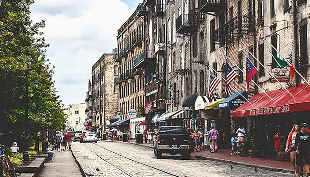 The image depicts a bustling historic city street with pedestrians parked cars and lined with American flags and various storefronts