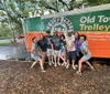 A group of cheerful people is posing for a photo in front of an Old Town Trolley Tours vehicle
