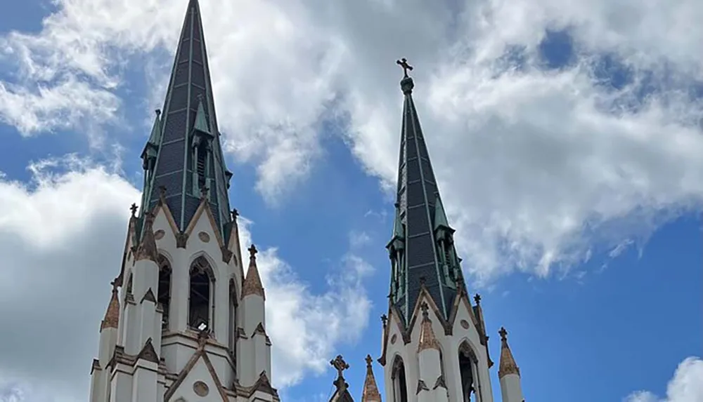 The image shows the ornate pointed spires of a gothic-style church reaching up into a partly cloudy sky