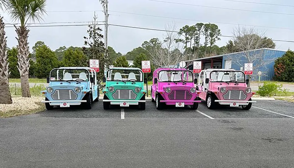 Four colorful vintage-style mini trucks are parked in a row showcasing hues of blue turquoise pink and a darker shade of pink