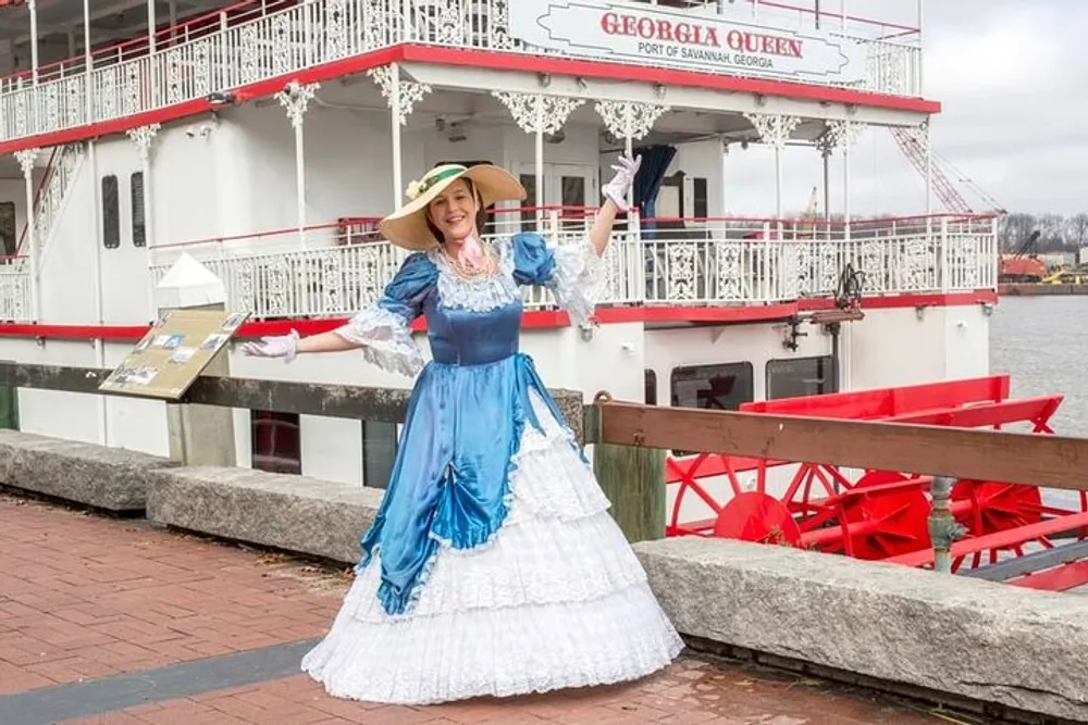 A person is wearing a historical costume and posing in front of the Georgia Queen riverboat
