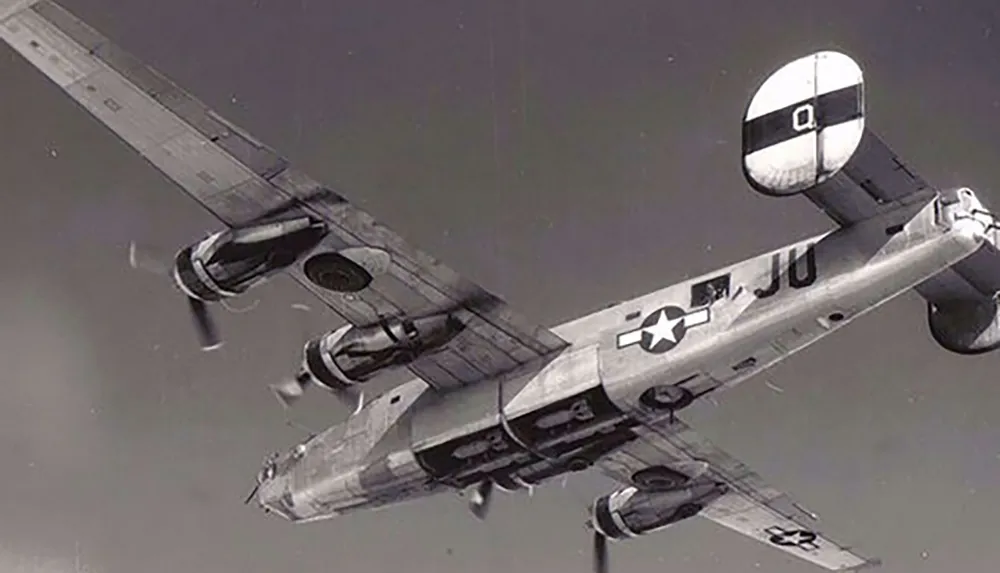 The image shows a vintage military airplane in flight captured from below clearly displaying its twin fuselage and distinctive twin-boom design