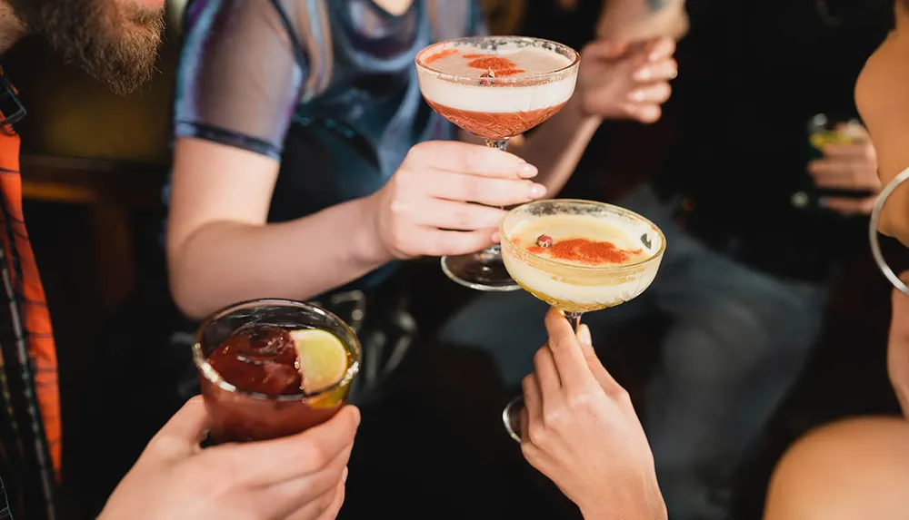 A group of people is toasting with various cocktails capturing a moment of social celebration