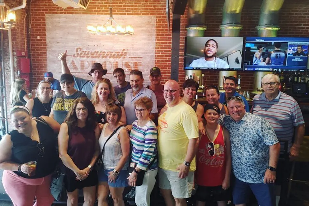 A group of smiling people is posing for a photo at a bar with a sign reading Samuel Adams in the background