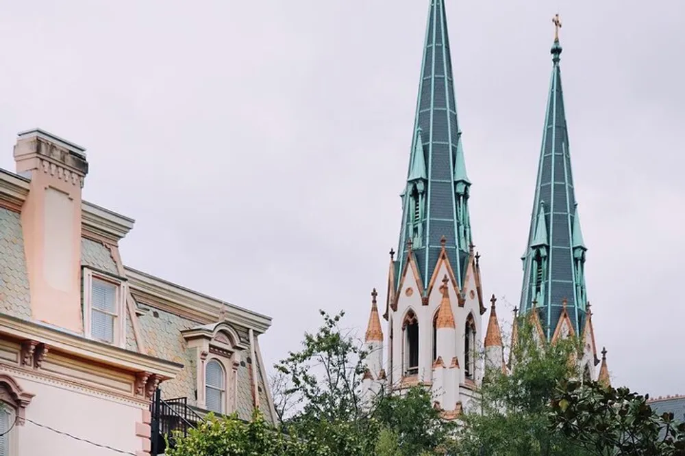 The image shows the ornate Gothic-style spires of a church rising above a row of classic houses on an overcast day
