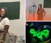 A man and a woman are smiling for a photo in a room with music equipment and a wall decorated with artificial greenery