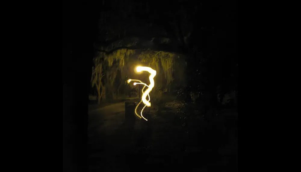 This image depicts a dark outdoor scene illuminated by a squiggly bright light trail that resembles an abstract or ghostly figure in the center