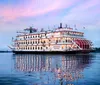 The image shows the Georgia Queen a large paddlewheel riverboat beautifully illuminated and adorned with festive lighting gliding along the water at twilight