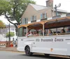 A group of people are riding a white trolley labeled Old Savannah Tours near a historic building with a sign for the Pirates House