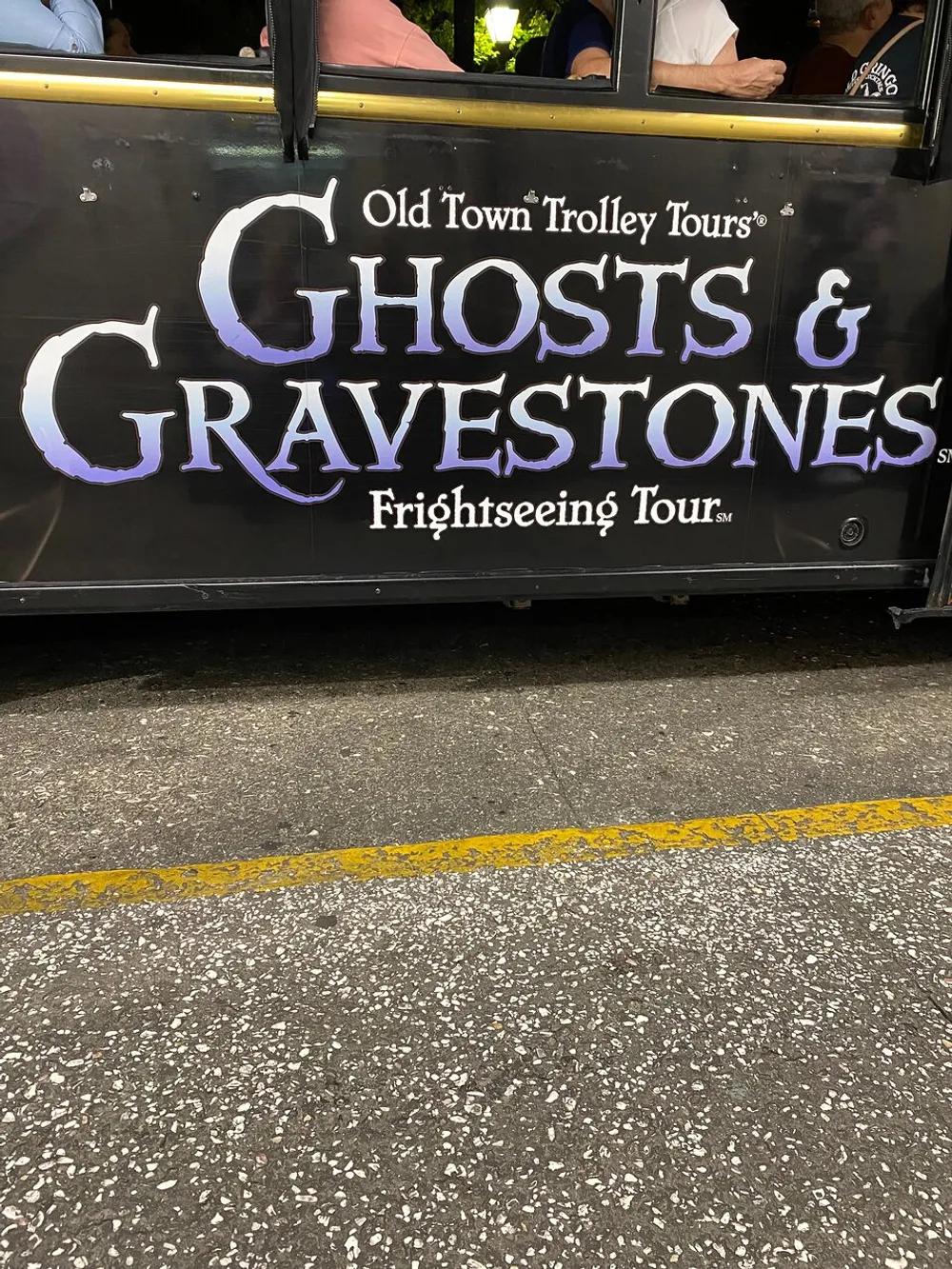 The image shows the side panel of a trolley tour vehicle advertising the Old Town Trolley Tours featuring Ghosts  Gravestones with a Frightseeing Tour tagline suggesting a themed sightseeing experience focused on haunted locales