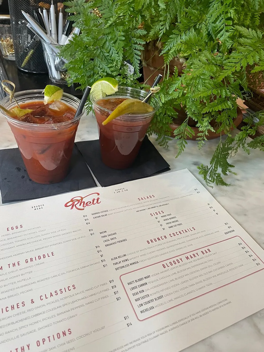 Two Bloody Mary cocktails are placed on a bar beside a brunch menu suggesting a leisurely dining experience