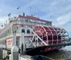 The image shows the Georgia Queen a large red and white paddlewheel riverboat docked at a pier under a blue sky