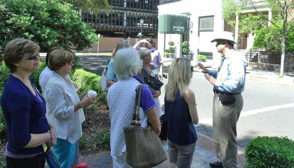 A group of individuals attentively listening to a tour guide speaking outdoors