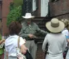 A tour guide in a wide-brimmed hat is explaining something to a group of attentive women on a city street