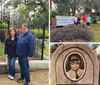 A family of four is posing for a photo in front of an ornate metal gate that leads to a cemetery with mature trees and tombstones in the background