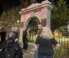 A group of people is gathered at night around a historic monument with the inscription DAR and an eagle statue on top commemorating the patriots of the American Revolutionary War from 1775-1783