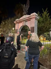 A group of people is gathered at night around a historic monument with the inscription 
