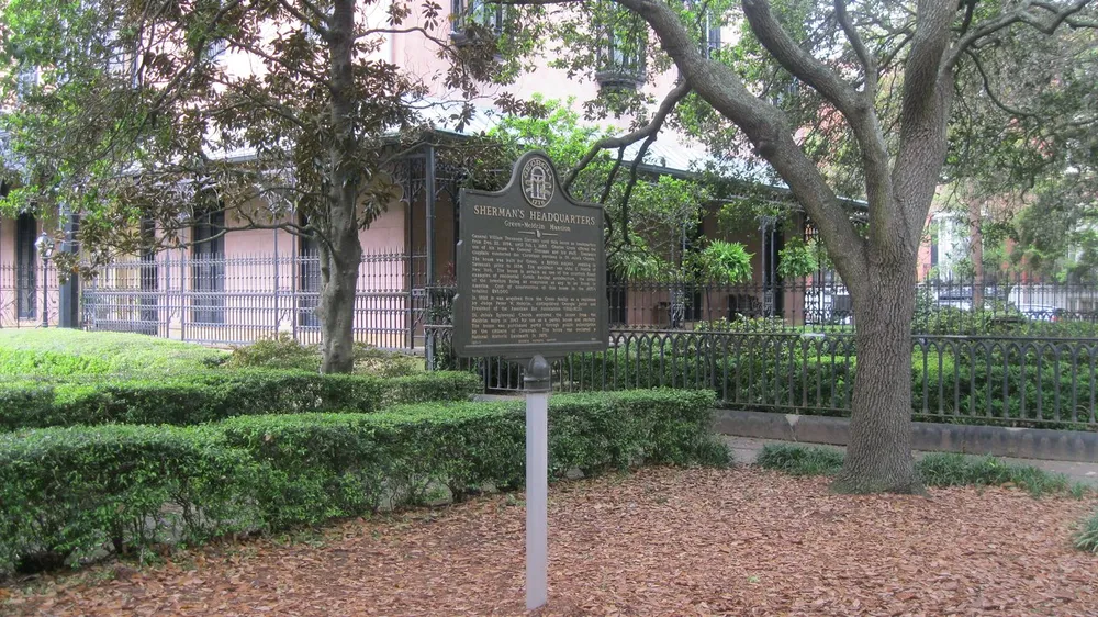 The image shows a historical marker titled Shermans Headquarters Green-Meldrim Mansion in a leaf-strewn garden with a wrought iron fence and trees likely indicating a significant historic site