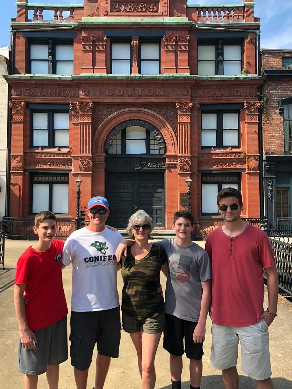 A group of five people is standing in front of the Savannah Cotton Exchange building on a sunny day