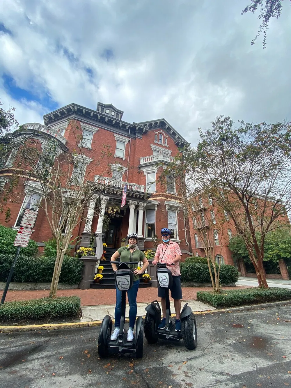 Two people are standing on Segways in front of a grand historic building with overcast skies above