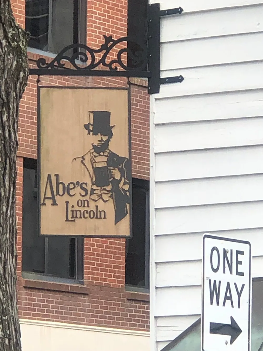 The image features a sign depicting a figure resembling Abraham Lincoln holding a drink with the text Abes on Lincoln above a one-way street sign