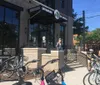 The image shows a sunny day outside a modern brick building that houses a business called Savannah On Wheels with several bicycles parked in racks out front