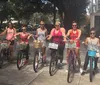 A group of smiling people are standing with rented bicycles in front of a house with a charming facade