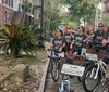 A group of smiling people are standing with rented bicycles in front of a house with a charming facade