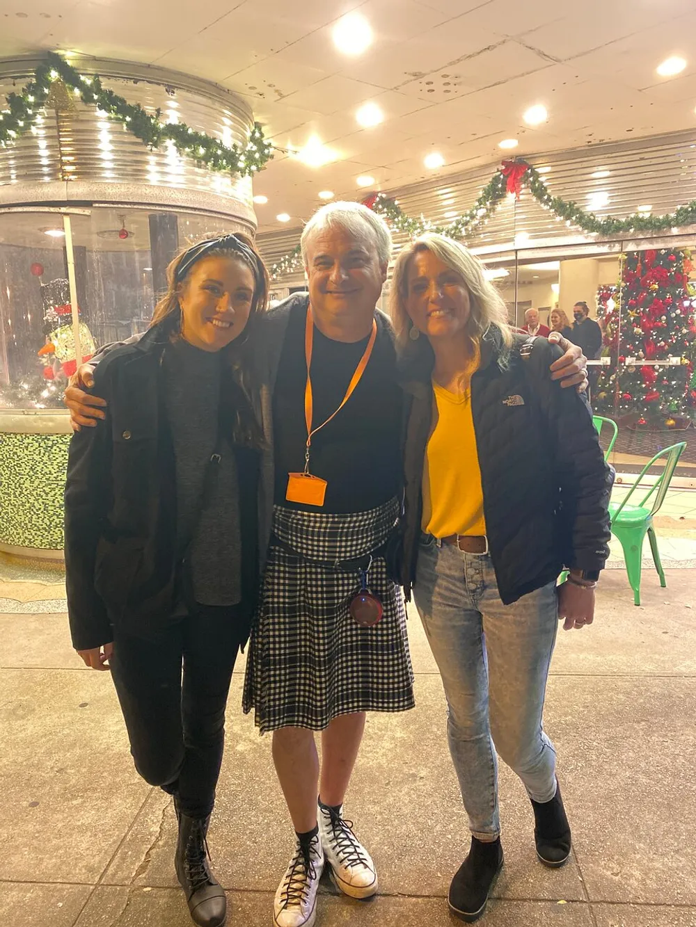Three people are smiling for a photo together with festive decorations in the background