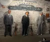 The image appears to be an exhibit at the American Prohibition Museum showing a criminal lineup featuring models or mannequins representing notable figures from the Prohibition era accompanied by placards with names like Bugs Moran Al Capone and Machine Gun Jack McGurn presented in front of a vintage cars headlight