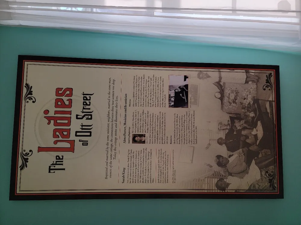 The image shows a framed informational poster titled The Ladies of Orr Street featuring text and historical photographs displayed on a wall with light teal paint