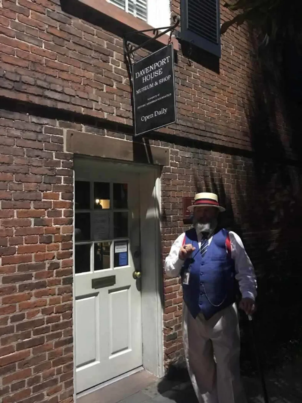 A person in historical dress stands beside the entrance to the Davenport House Museum  Shop which is signposted as open daily
