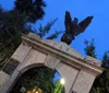 The image depicts a gate with an eagle sculpture on top marked DAR at twilight under a crescent moon leading into what appears to be a historical site or cemetery