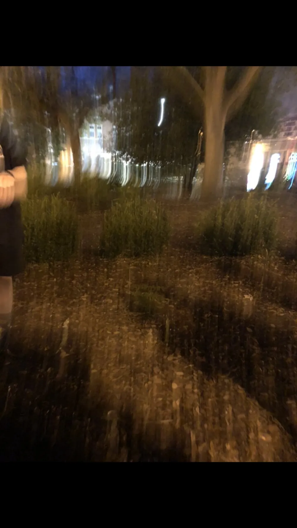 The image is a blurred nighttime scene possibly depicting an outdoor environment with lights streaking due to camera movement