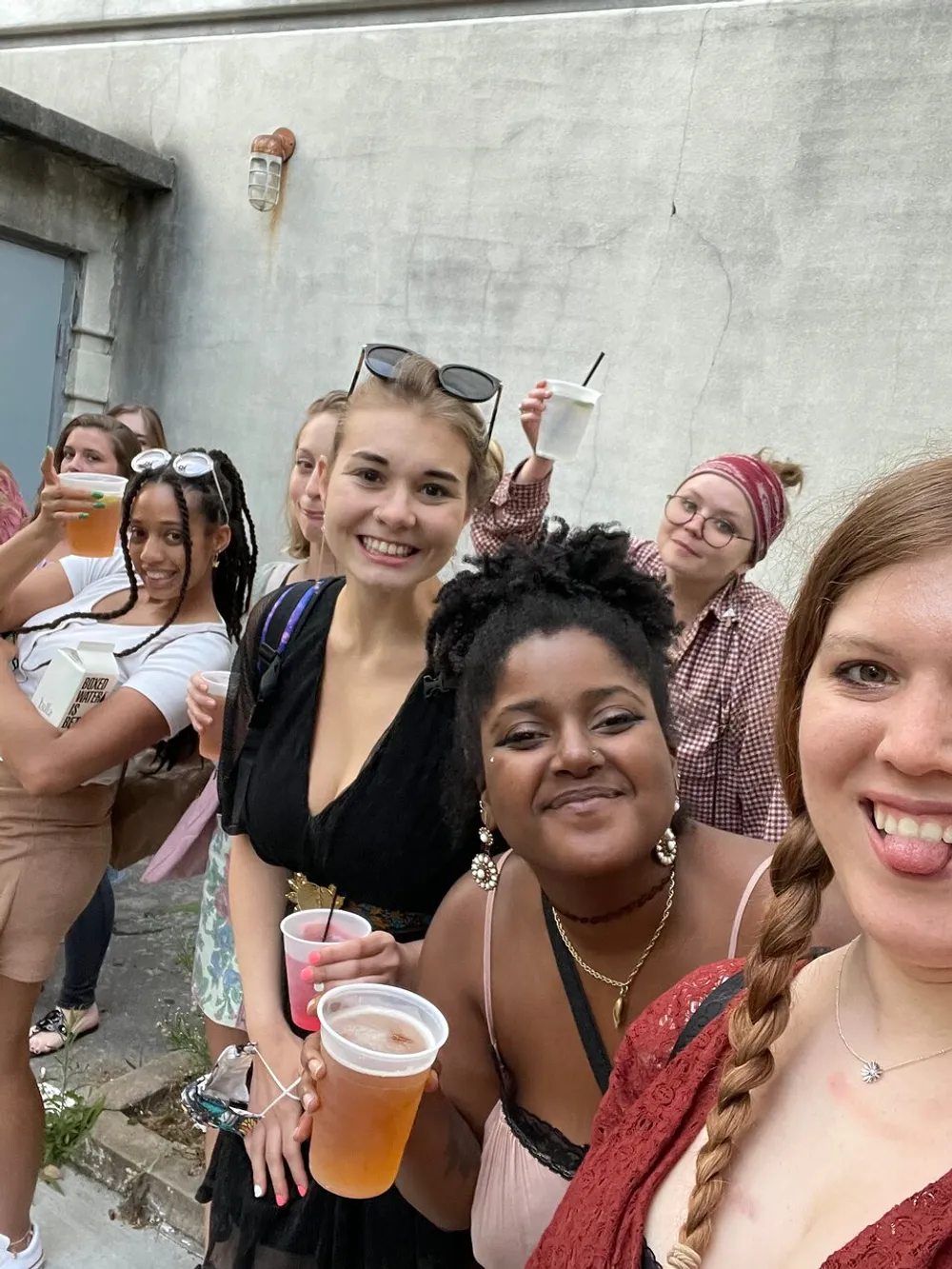 A group of people are taking a cheerful selfie together while holding drinks suggesting a social gathering or celebration