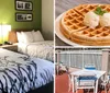 The image shows a hotel room with two queen-sized beds featuring white bedding with a black tree branch pattern a nightstand with a lamp and phone between the beds and a green accent wall with framed artwork