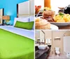 The image displays a bright and colorfully decorated hotel room featuring a bed with a green bedspread complemented by aqua walls patterned carpet and a vase with tall greenery on a wood-toned surface in the foreground