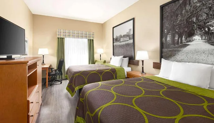 The image shows a neatly arranged double hotel room with two beds a desk a television and decorative wall art