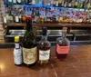 Three bottles of alcoholvermouth bourbon and ginare prominently displayed on a bar counter with an array of spirits in the background
