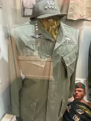 The image displays a mannequin dressed in a military uniform with a name tag reading 