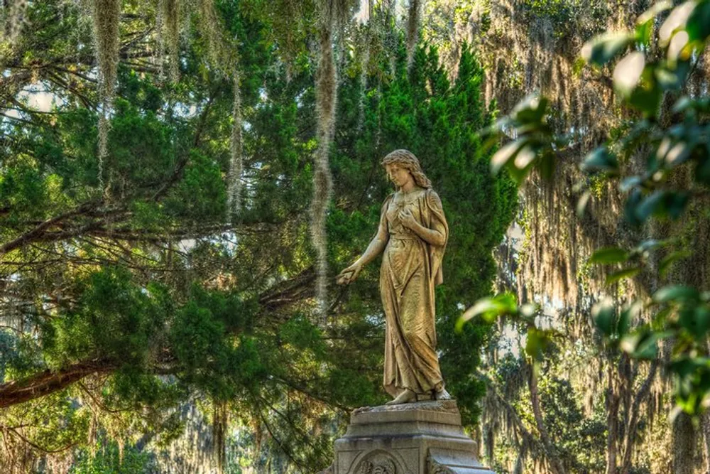 A weathered statue of a woman stands gracefully among verdant trees draped with Spanish moss evoking a serene and timeless atmosphere