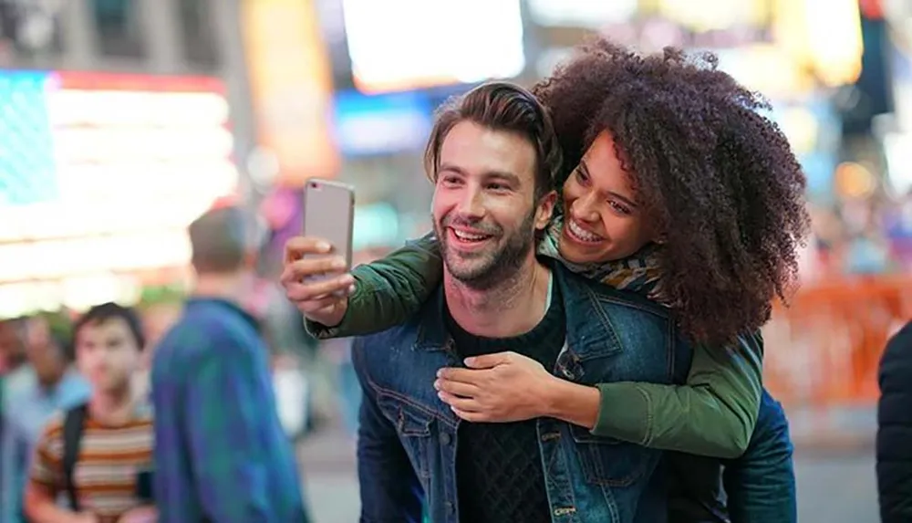 A happy couple is taking a selfie together with a bustling city street in the background