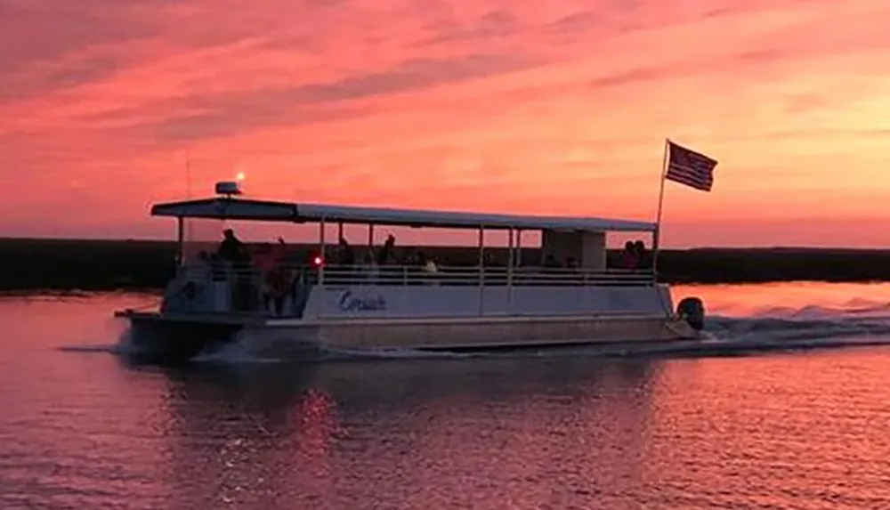 The image depicts a pontoon boat cruising on the water with passengers on board against a striking sunset sky painted in shades of pink and orange with an American flag flying at the stern