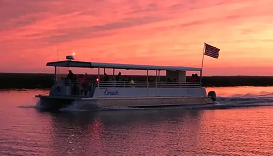 The image depicts a pontoon boat cruising on the water with passengers on board, against a striking sunset sky painted in shades of pink and orange, with an American flag flying at the stern.
