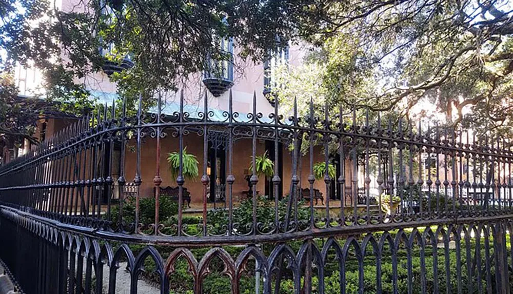 This image features a charming historical building behind an ornate iron fence with lush greenery and intricate balconies evoking a sense of Southern elegance