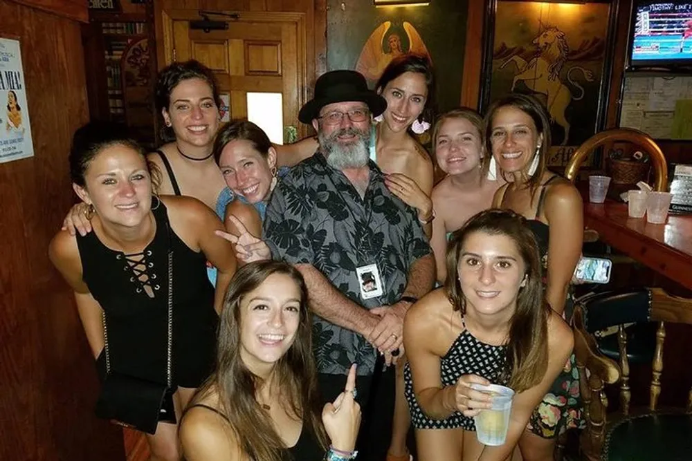 A group of cheerful people is posing for a photo inside a bar with one man and several women smiling and enjoying themselves