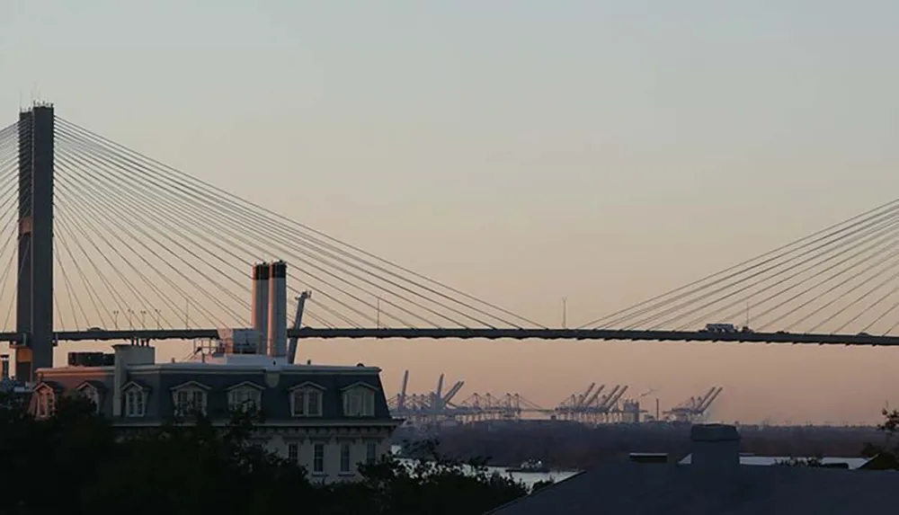 The image shows a cable-stayed bridge dominating the skyline at dusk with a classical building in the forefront and industrial elements in the background